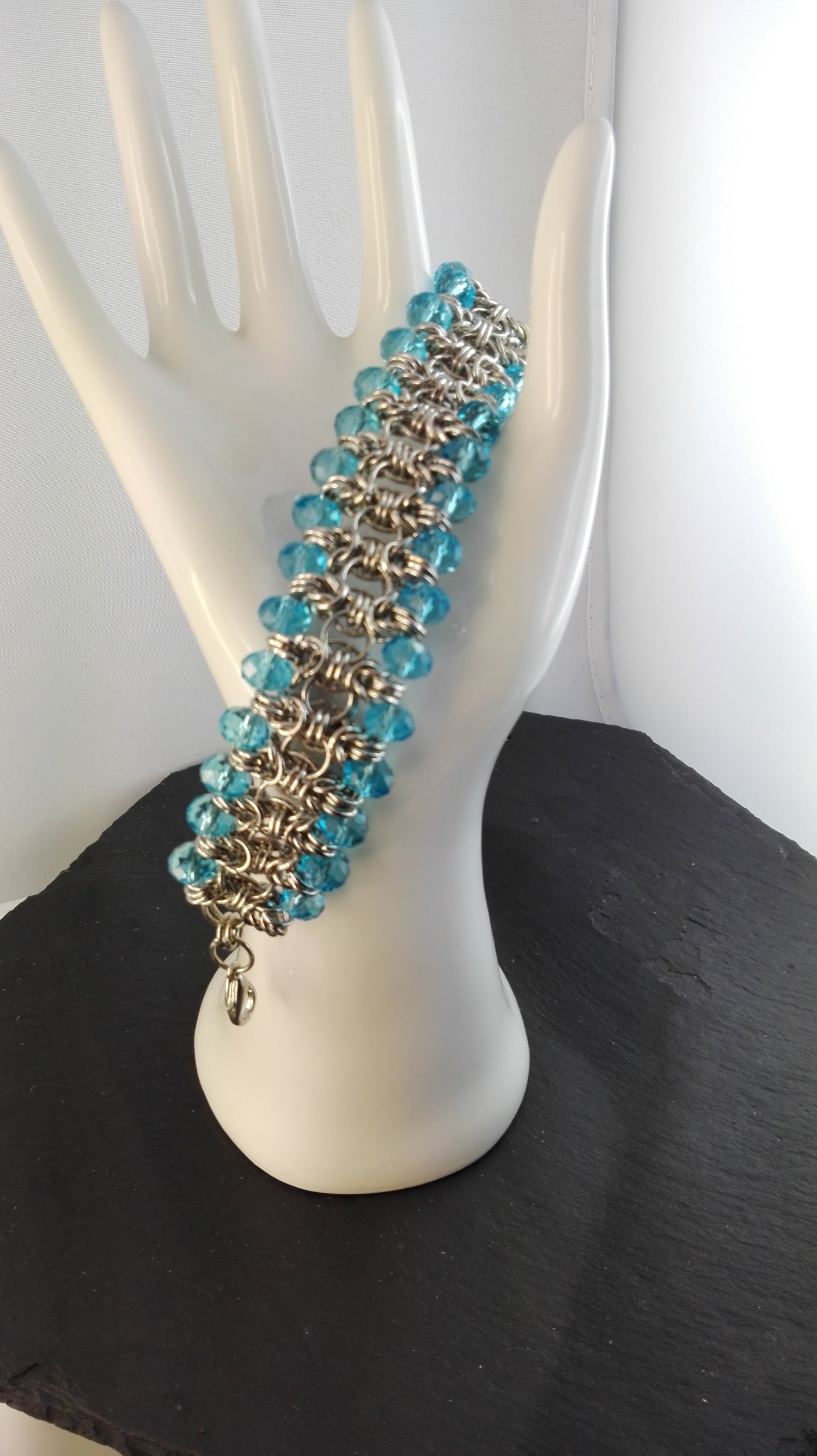 Chainmaille. Früher im Mittelalter als Kettenhemdtechnik bekannt. Hierbei werden viele einzelne Binderinge zu einem komplexen Schmuckstück zusammengebaut. Das funktioniert mit purer Handarbeit.